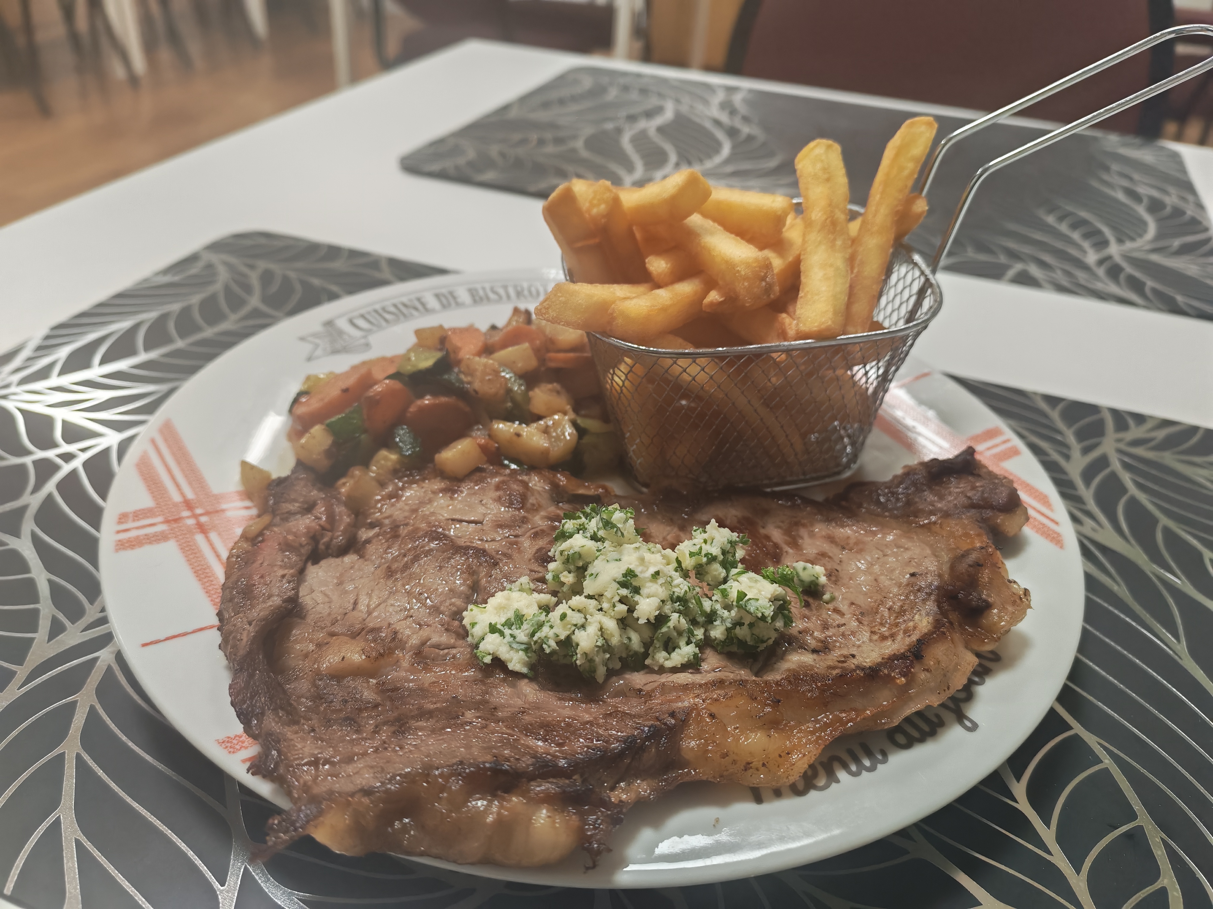 Photo d'une pièce de bœuf au beurre persillé et son accompagnement frites, poêlée de légumes et salade verte